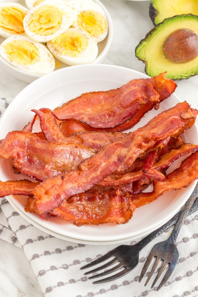 bacon on a plate on the table with boiled eggs and avocado