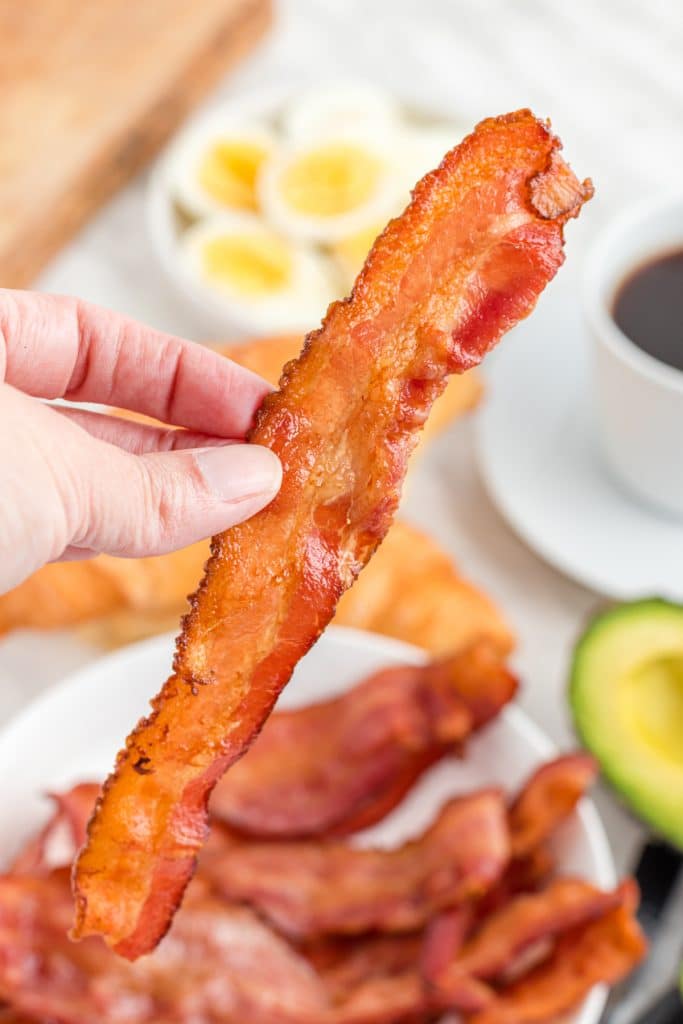 hand holding a slice of bacon cooked in the air fryer