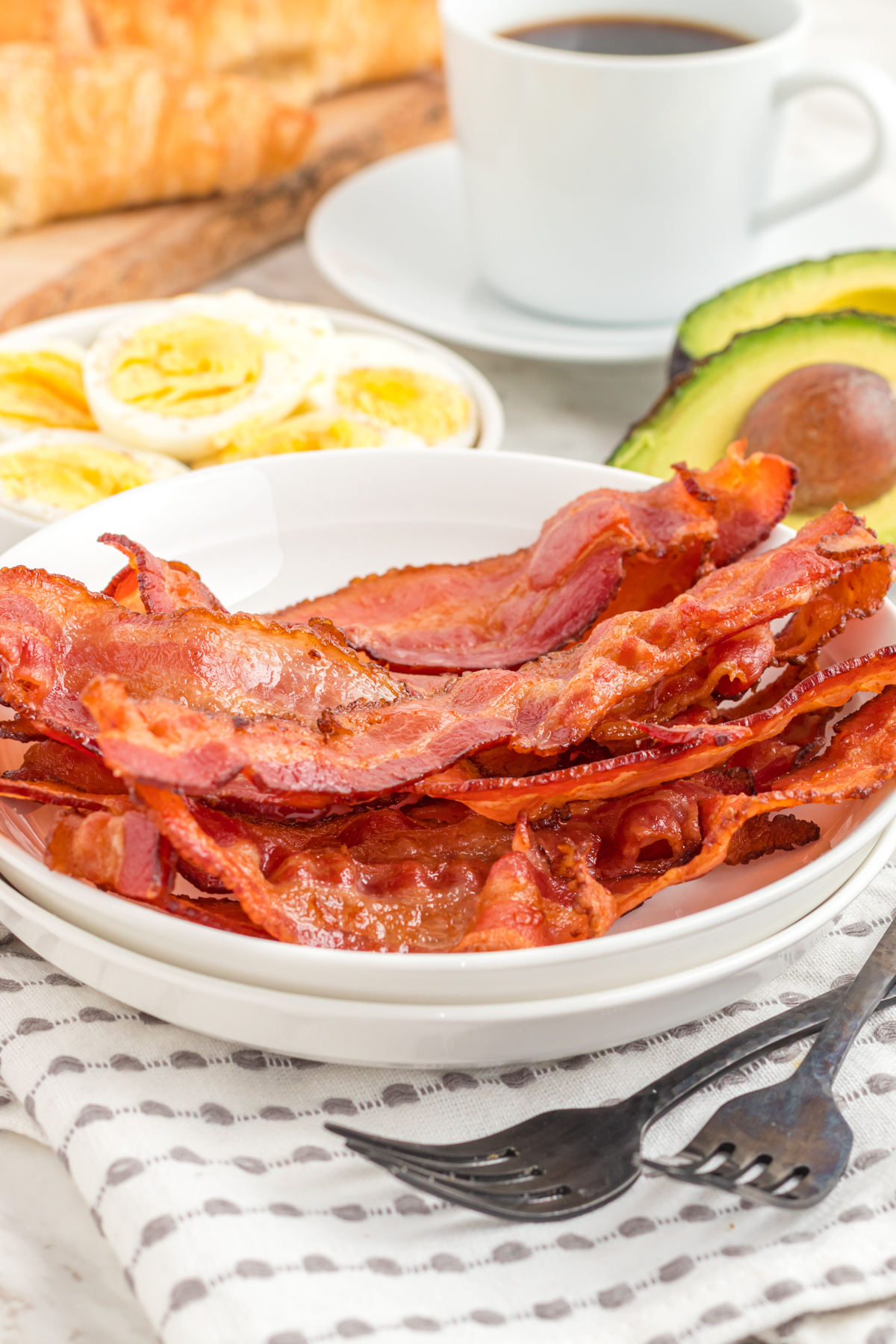 bacon in the air fryer on a plate with eggs and avocado in side dishes
