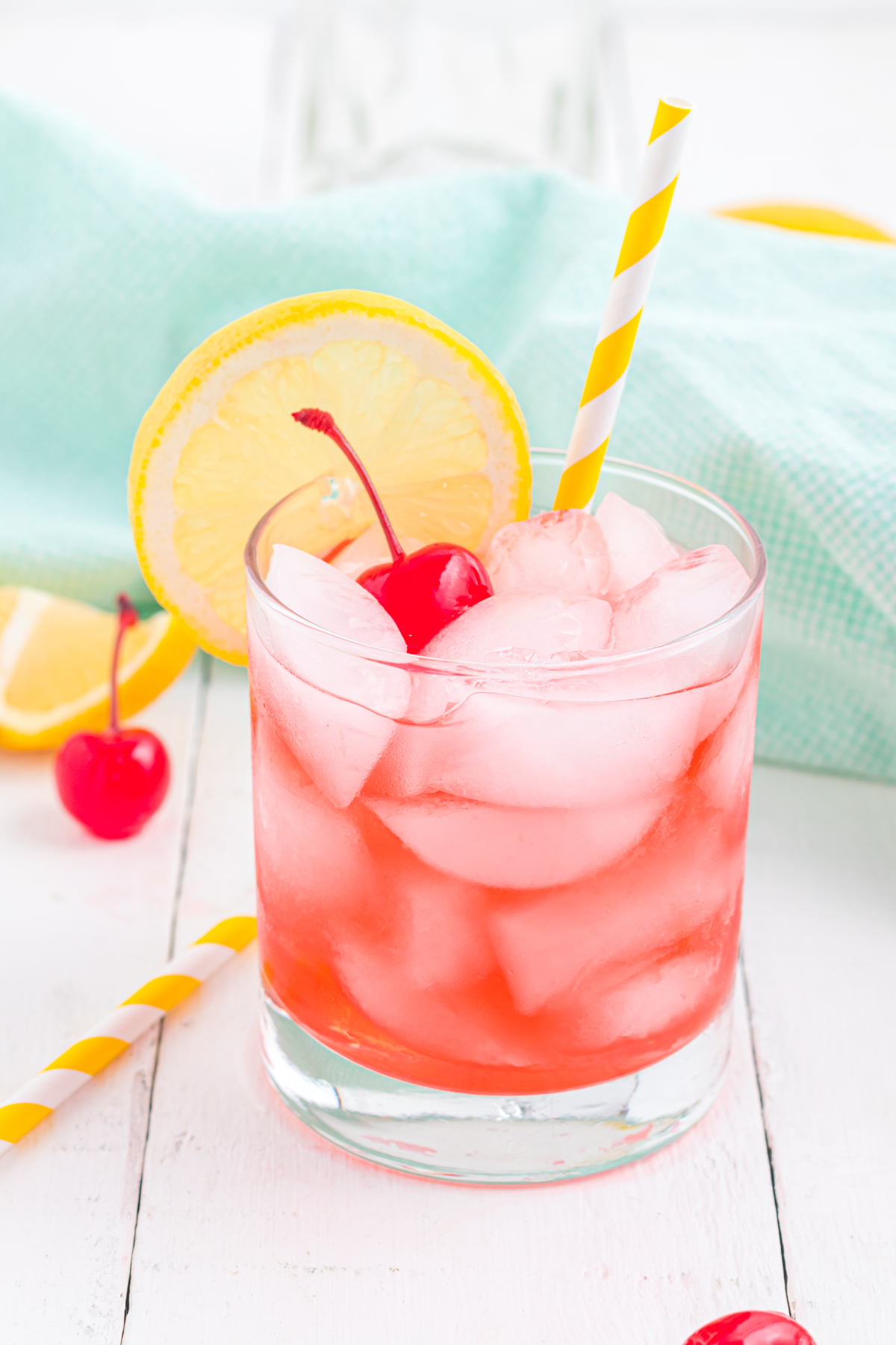Cherry Vodka sour with a yellow straw and maraschino cherry and lemon slice for garnish