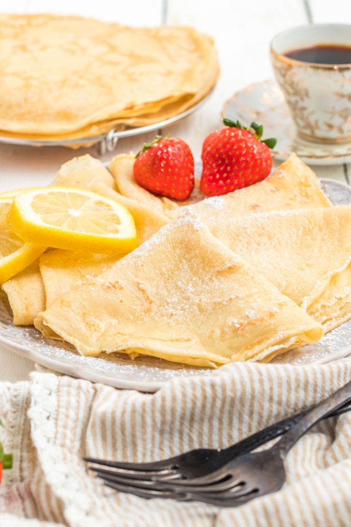 Parisian Crêpes  on a plate with lemon and strawberries and espresso