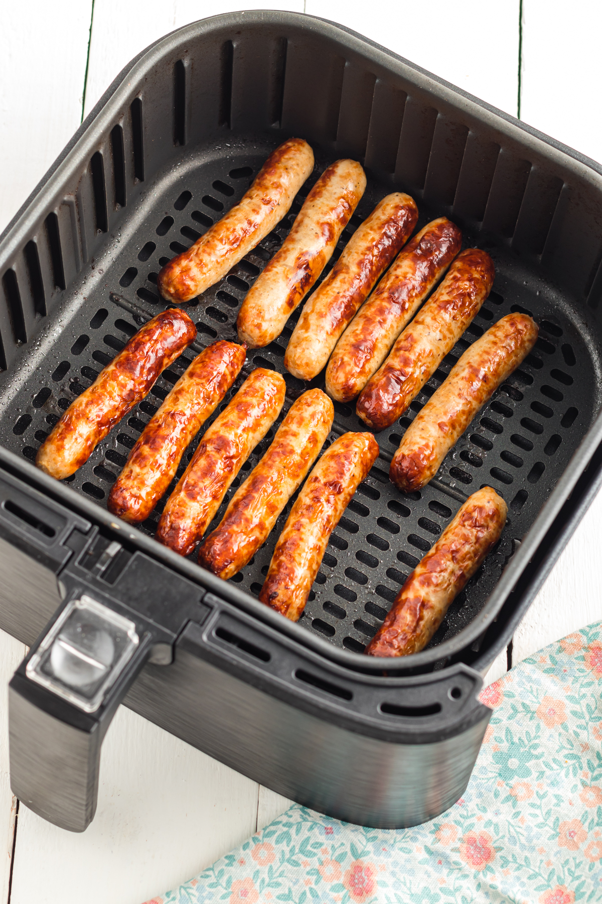 Sausage links in air fryer basket.