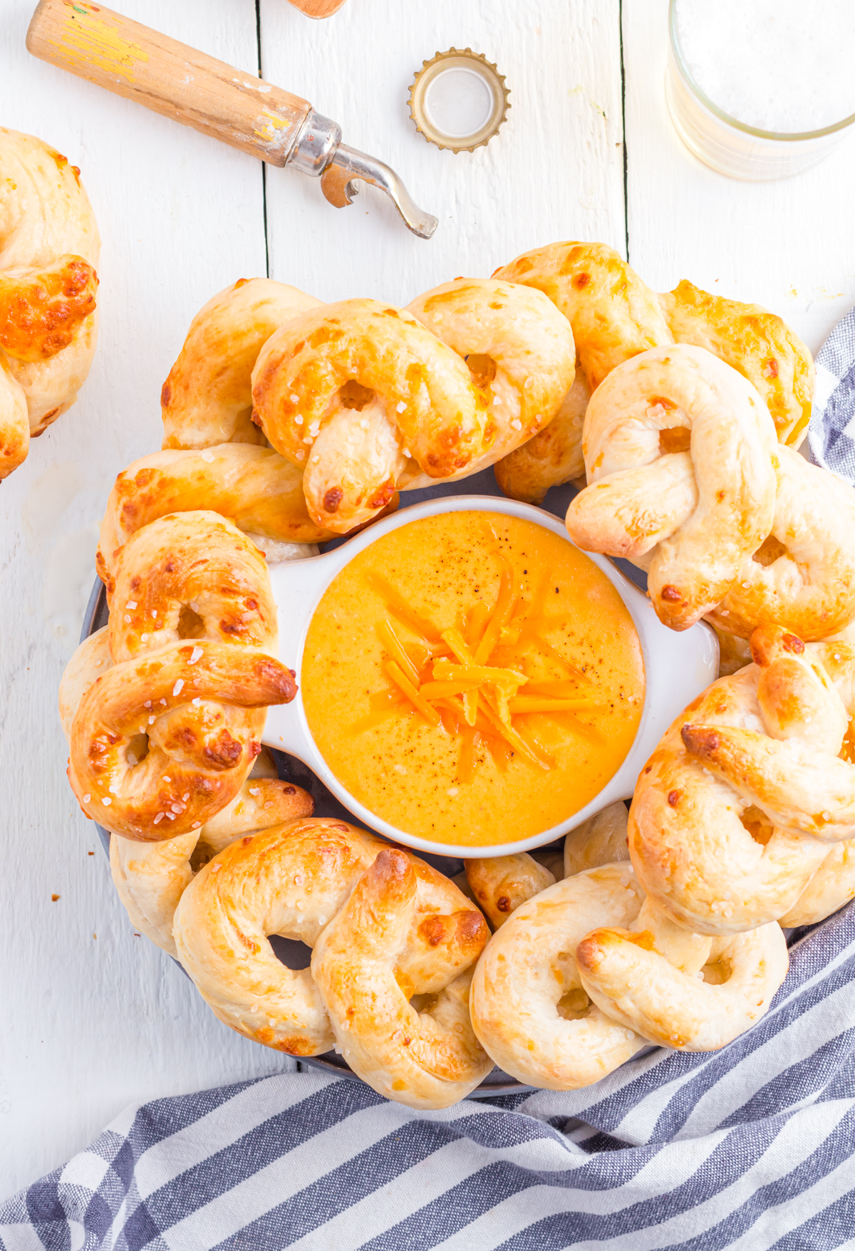 Beer cheese dip for pretzels in bowl, surrounded by soft pretzels.