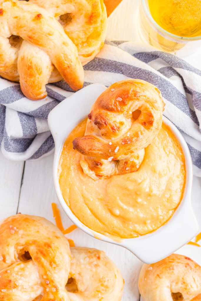 Soft pretzel dipped in a bowl of  cheese dip.