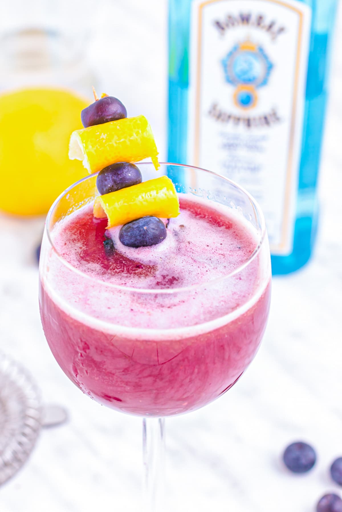 Blueberry Gin Sour Cocktail garnished with blueberries and lemon.