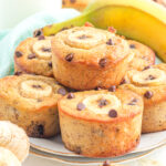 Banana chocolate chip muffins stacked on a plate.
