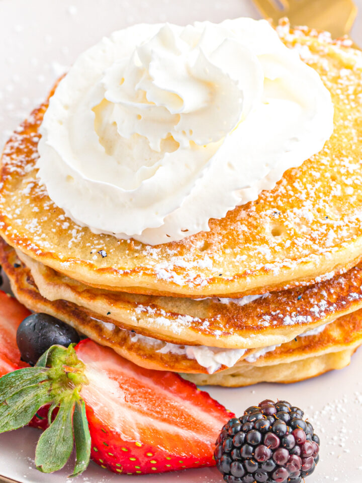 Sweet cream pancakes with whipped cream and berries.