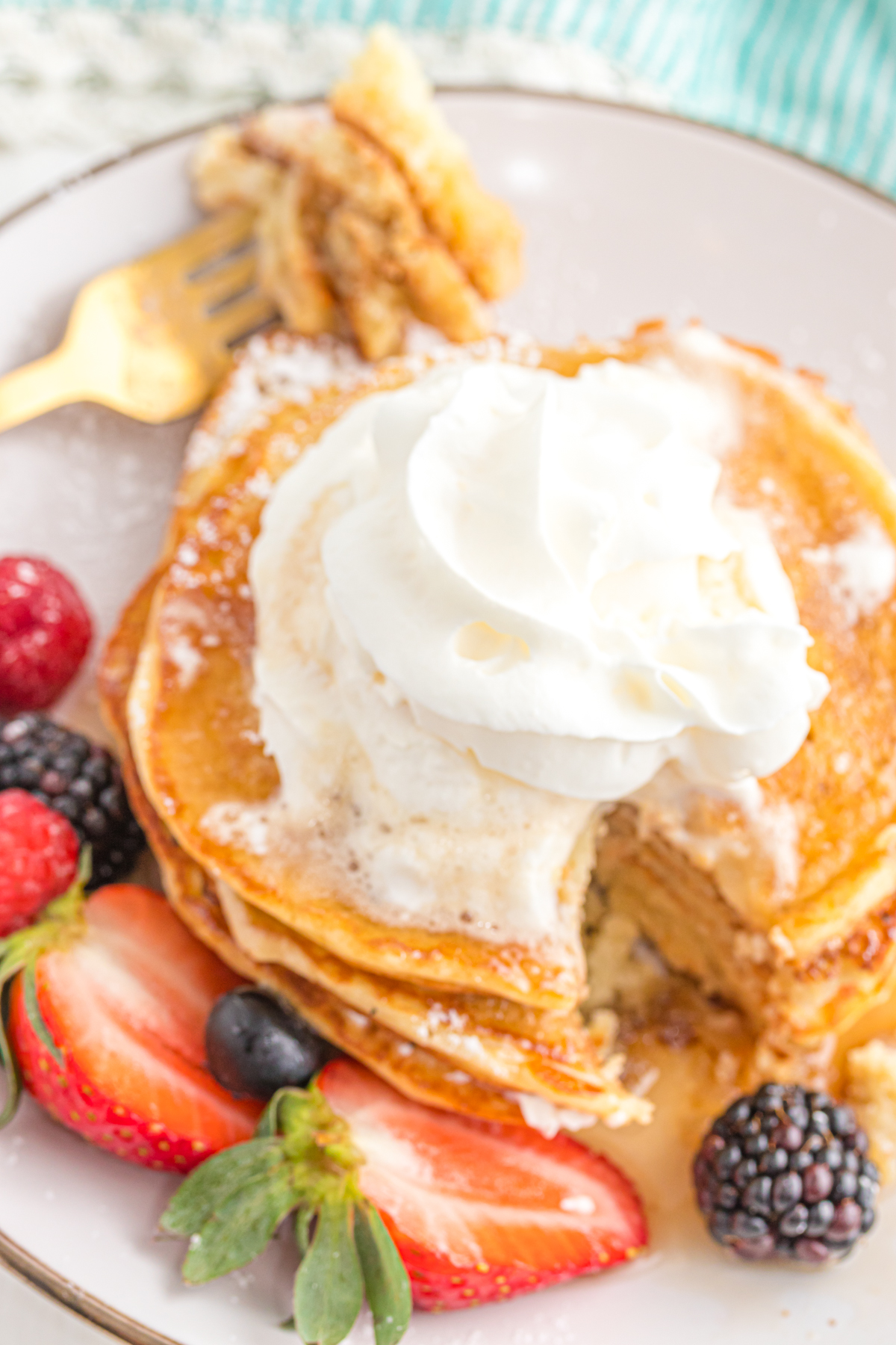 Pancakes on a plate topped with whipped cream.