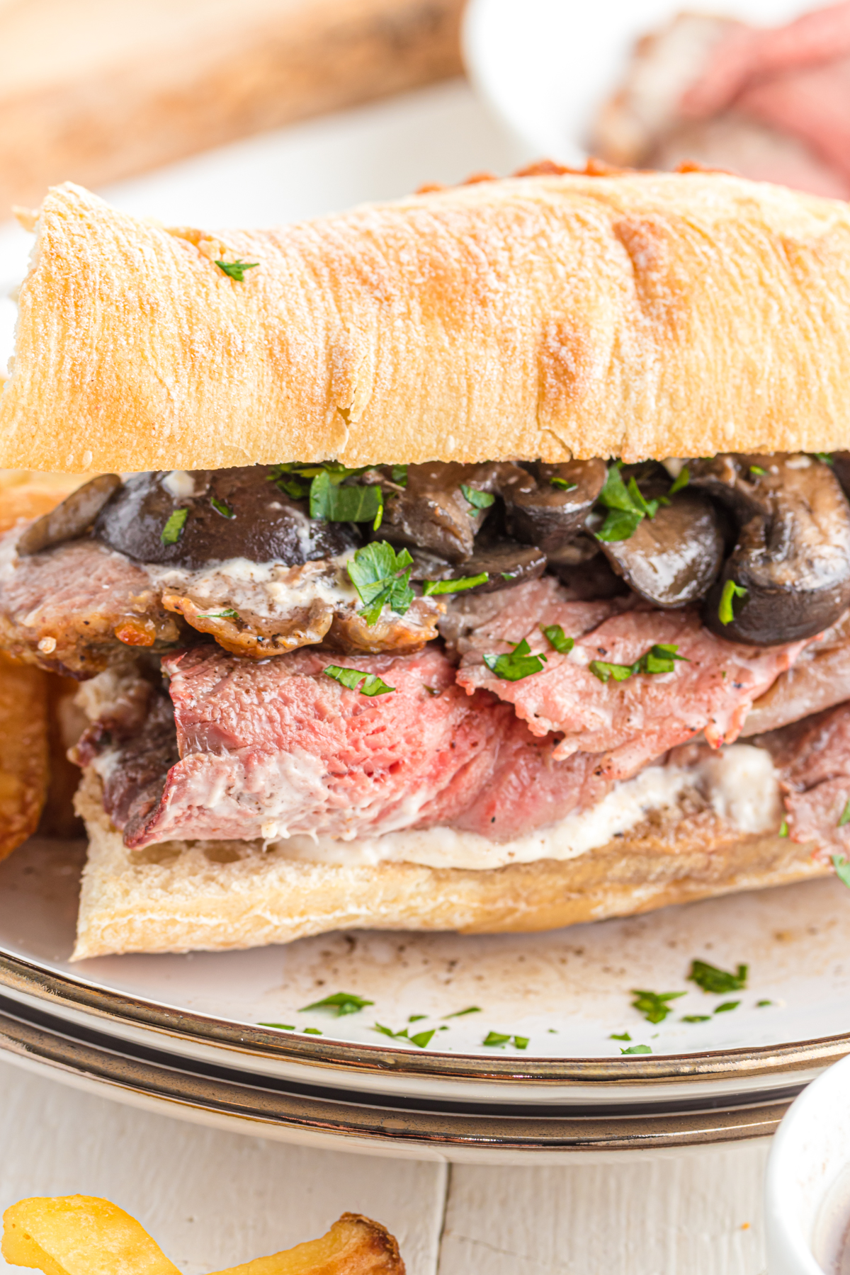 close up of roast beef sandwich with mushrooms and parsley.