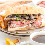 Prime rib sandwich on plate with fries.