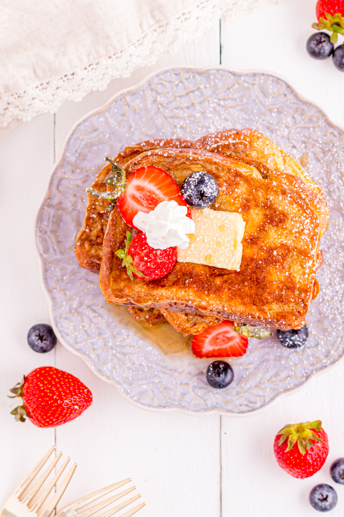 French toast with a square of butter and berries on a plate.