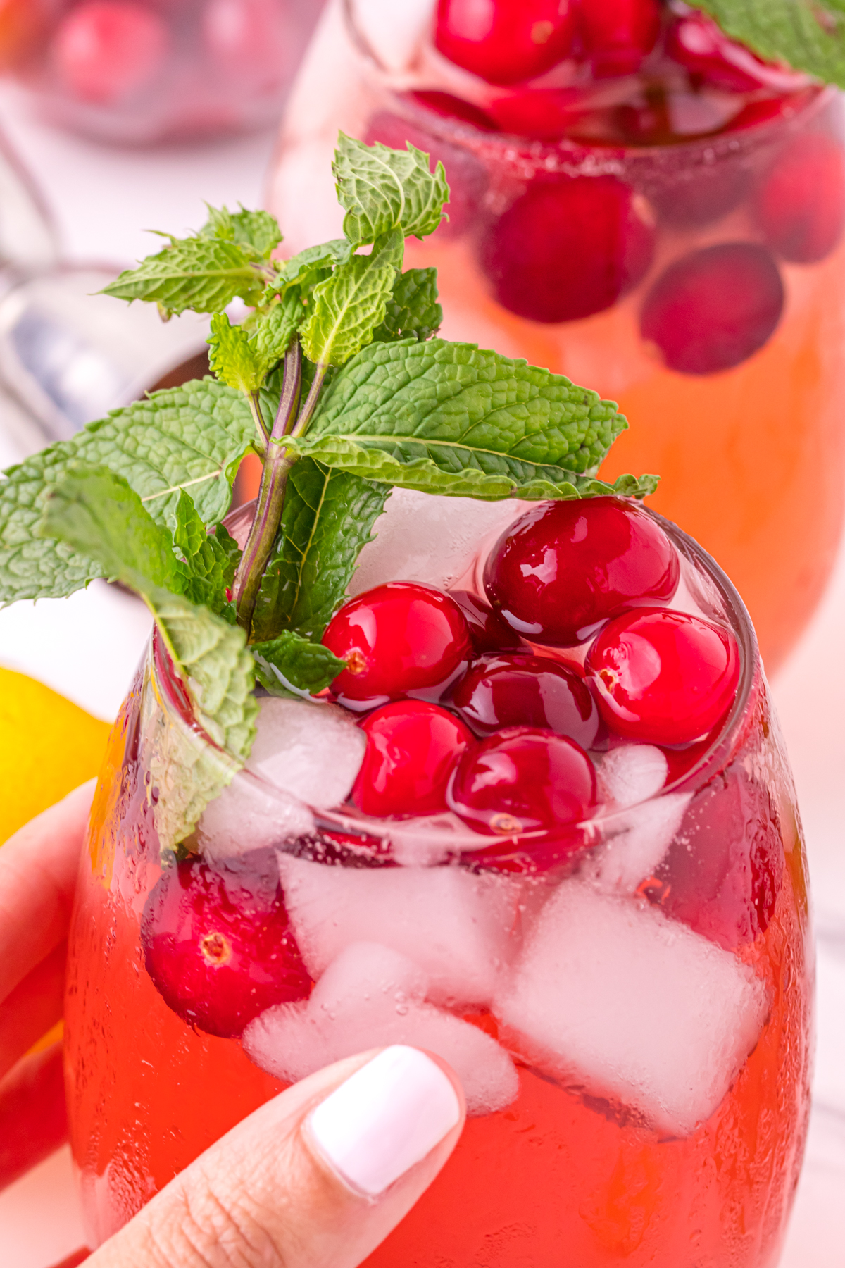 Holding cranberry drink with mint cranberries and ice.
