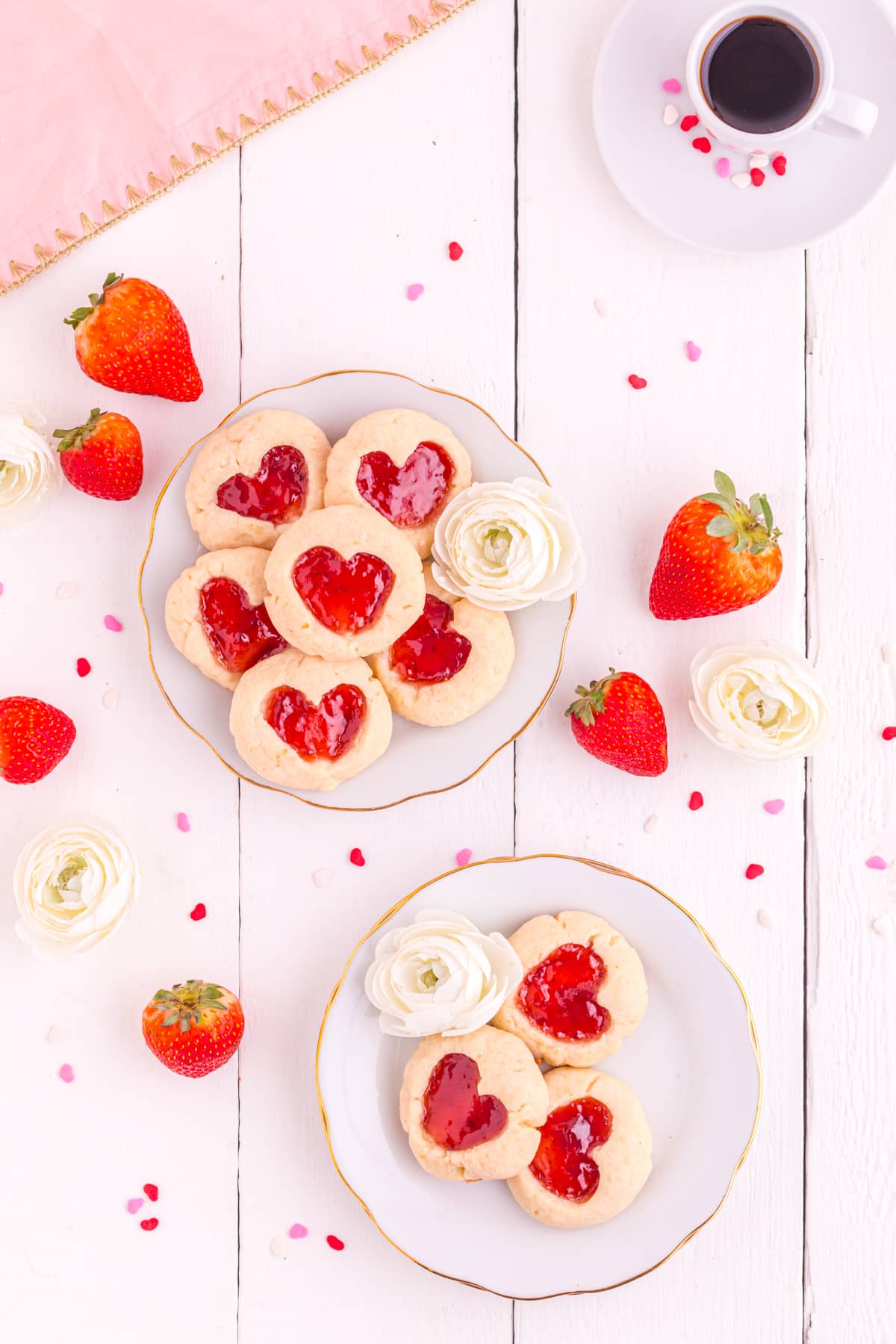 Heart thumbprint cookies on table with strawberries and espresso.