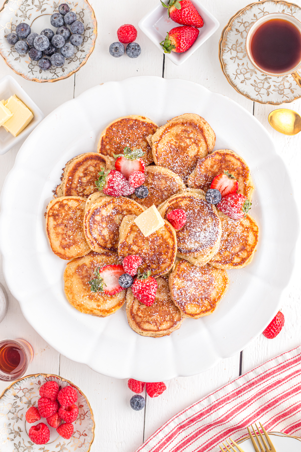 Silver dollar pancakes on round platter on table with berries.