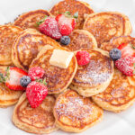 Plate of pancakes with powdered sugar and berries.