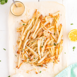 Parmesan truffle fries on parchment paper on a table.