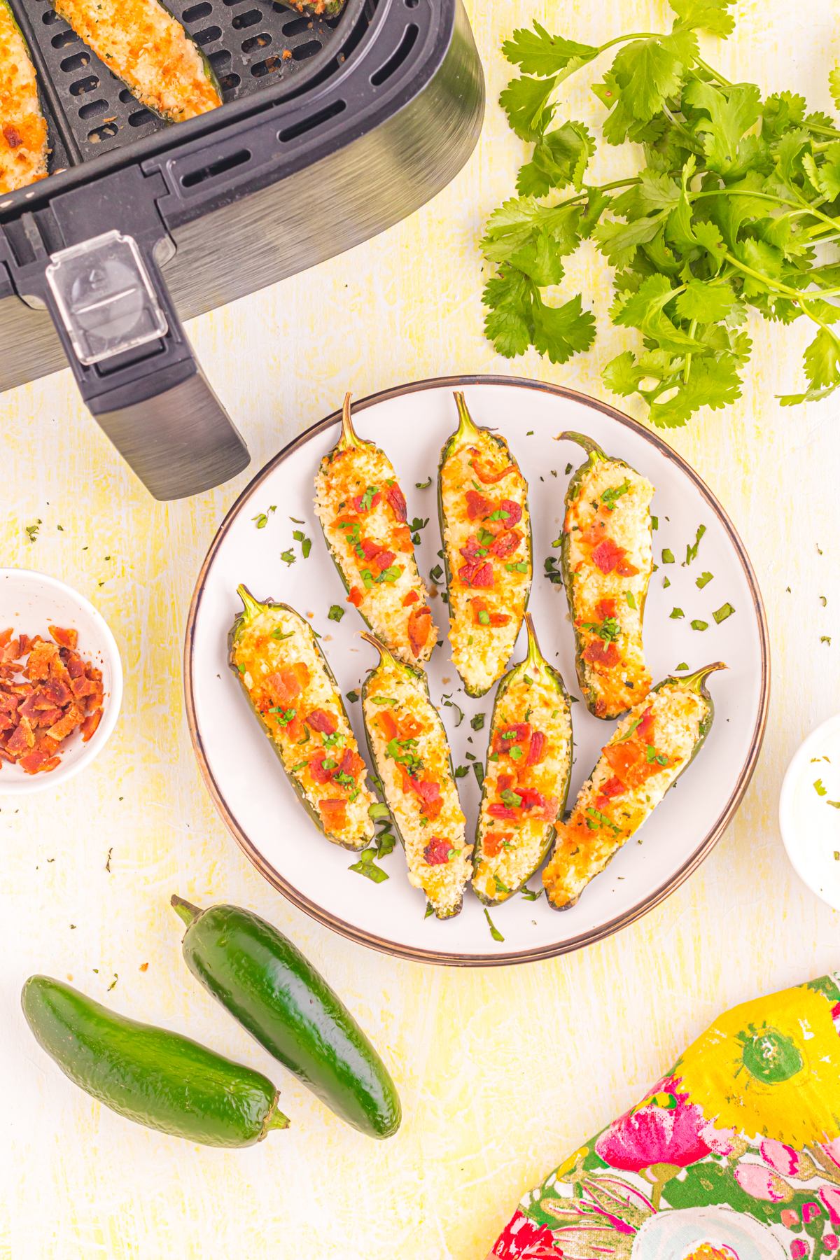 Jalapeno poppers on table with air fryer and ingredients.
