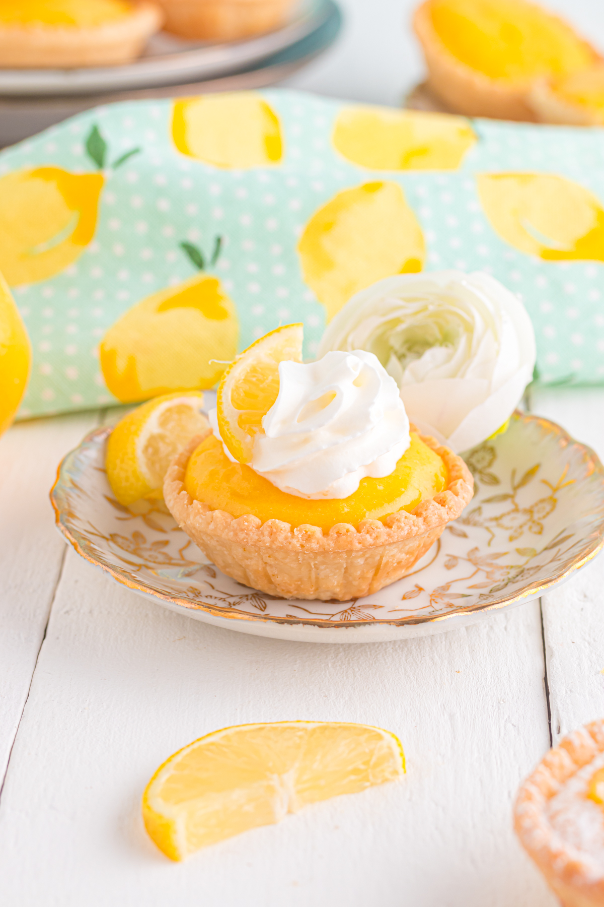 Mini lemon tarts on plate topped with whipped cream.