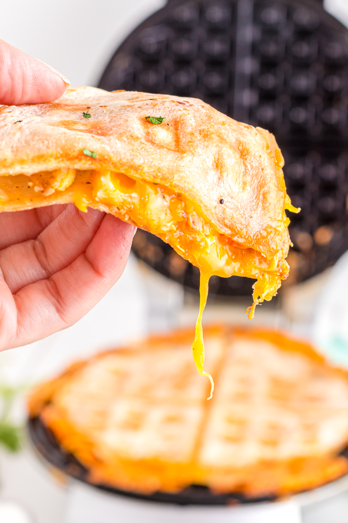 Quesadilla slice in hand with melted cheese dripping out.