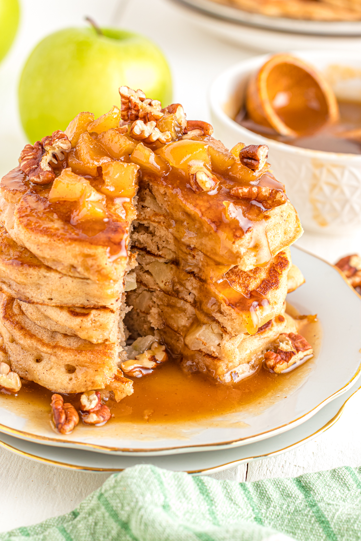 Stack of caramel apple pancakes with a bite cut out.