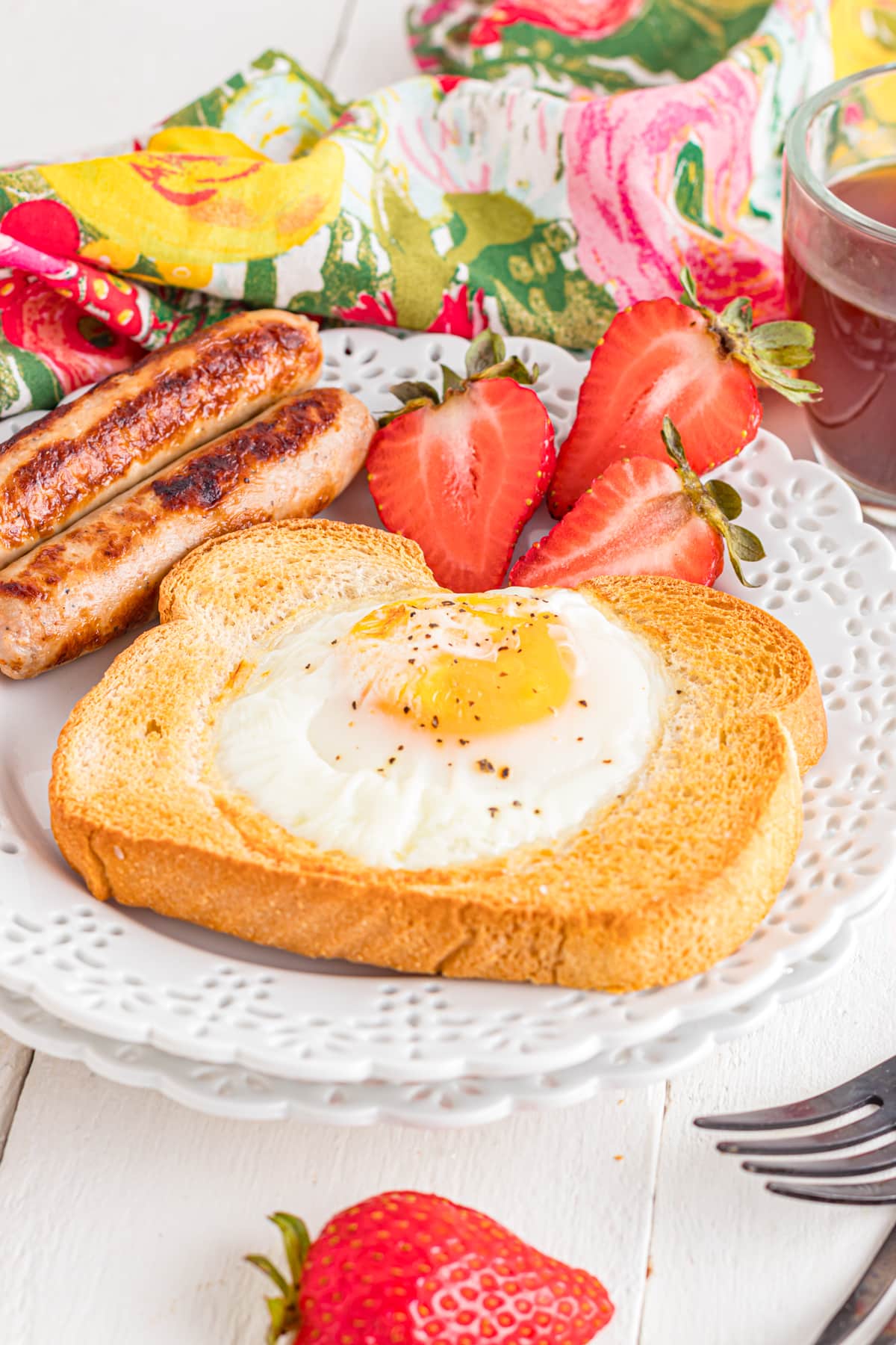 Air fryer egg toast on plate with sausages and strawberries.