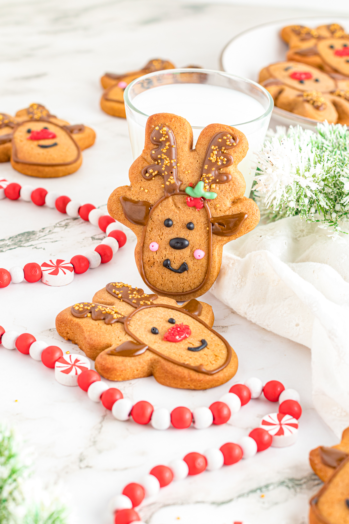 Gingerbread Reindeer Cookies on a table with a glass of milk.