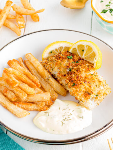 Panko crusted cod with fries and tartar sauce on a plate.