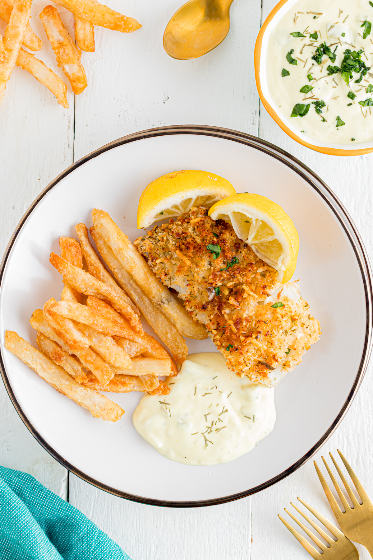 Breaded cod on plate with fries and tartar sauce.