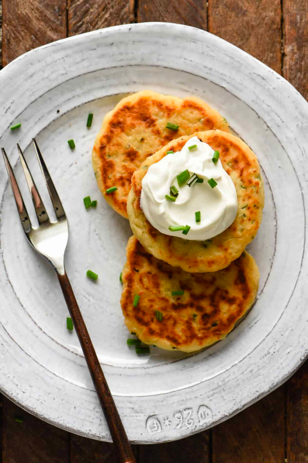 Potato cakes on plate with sour cream and chive topping.