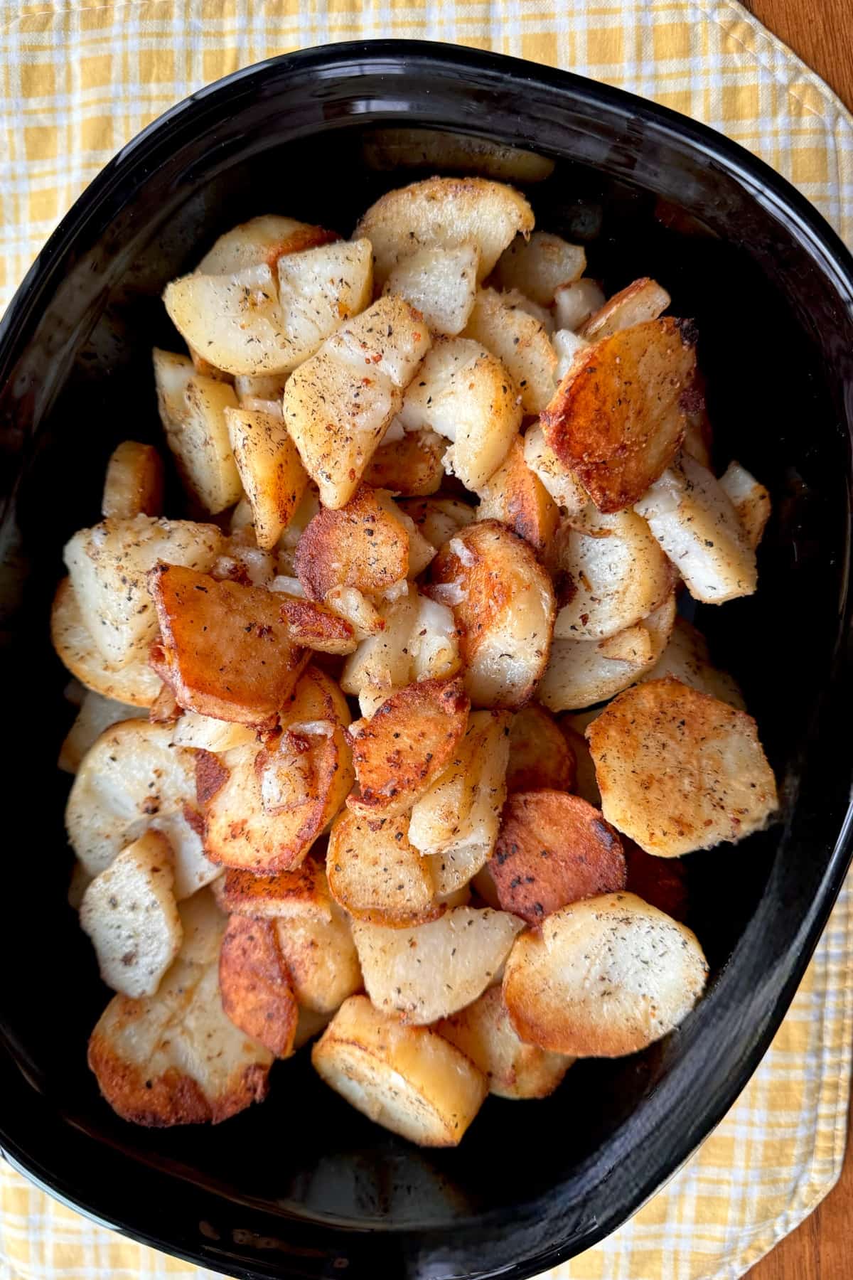 Fried potatoes in black serving dish.