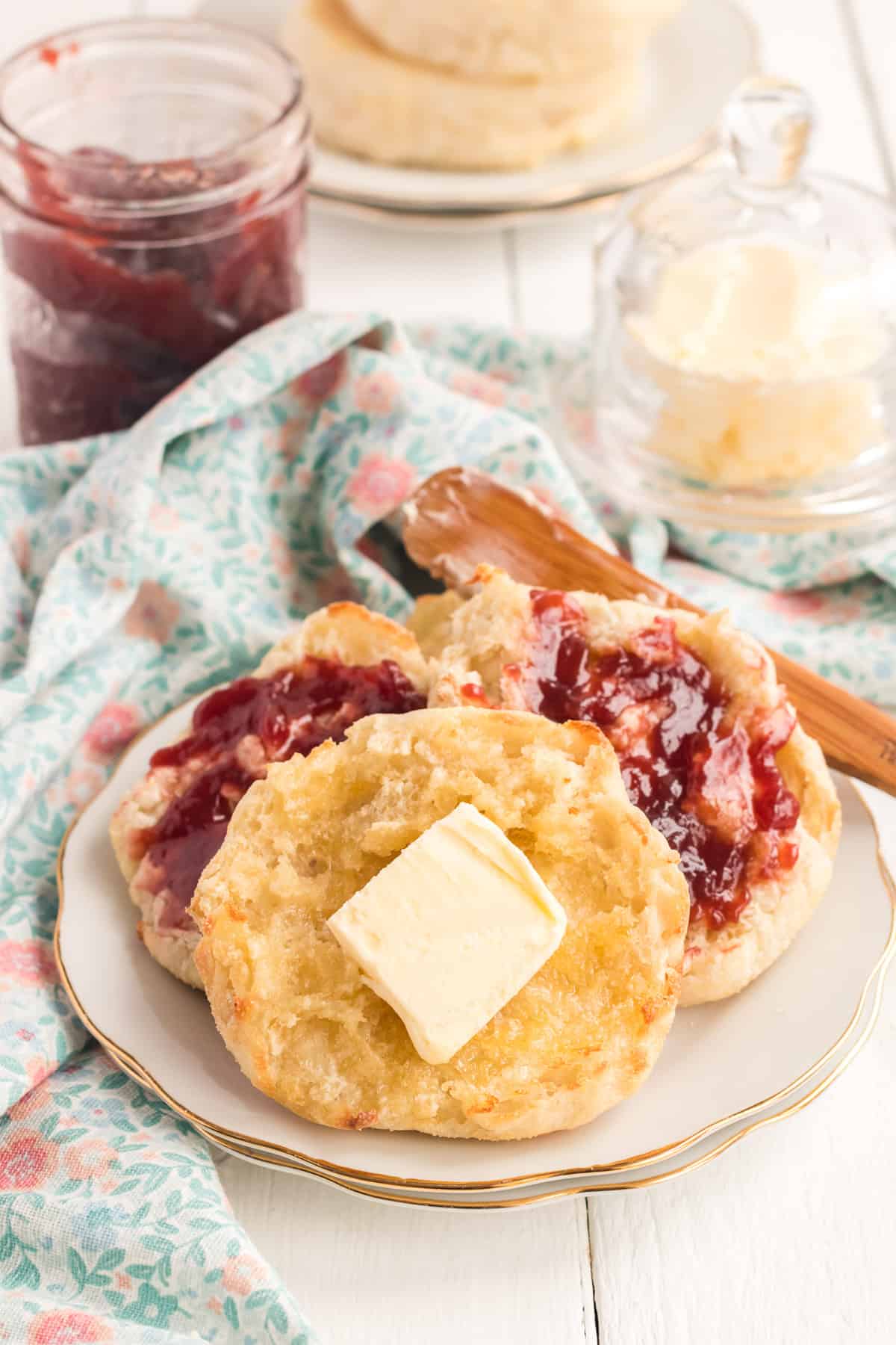 English muffins with butter and jam on plate.