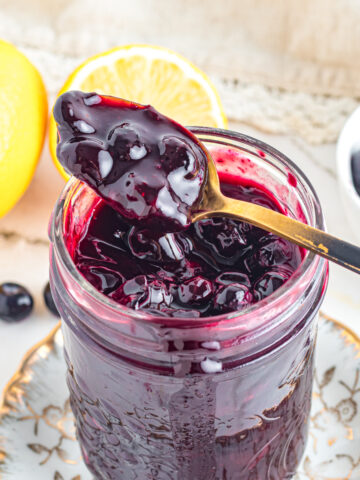 Blueberry Compote on spoon over jar.
