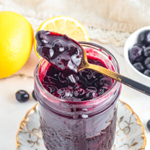 Blueberry compote in spoon over jar.