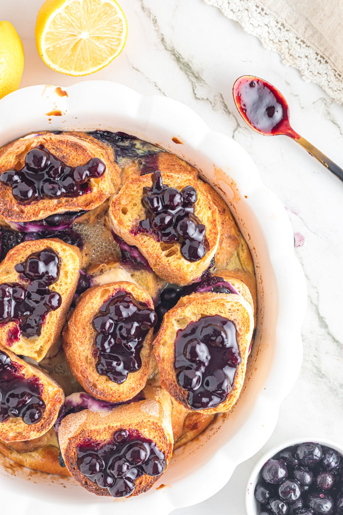 Blueberry French toast in white baking dish on table.
