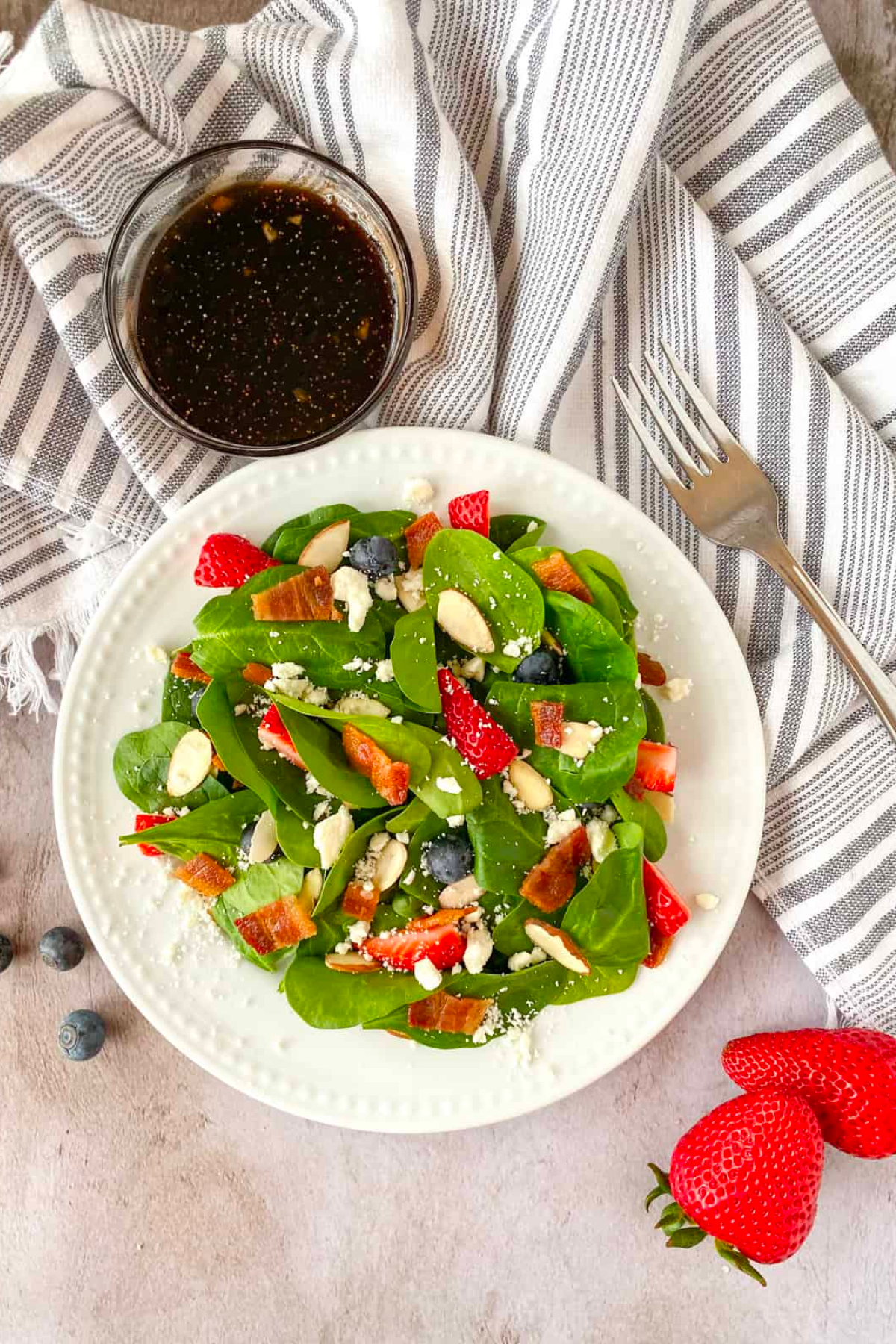 Strawberry spinach salad in white bowl.