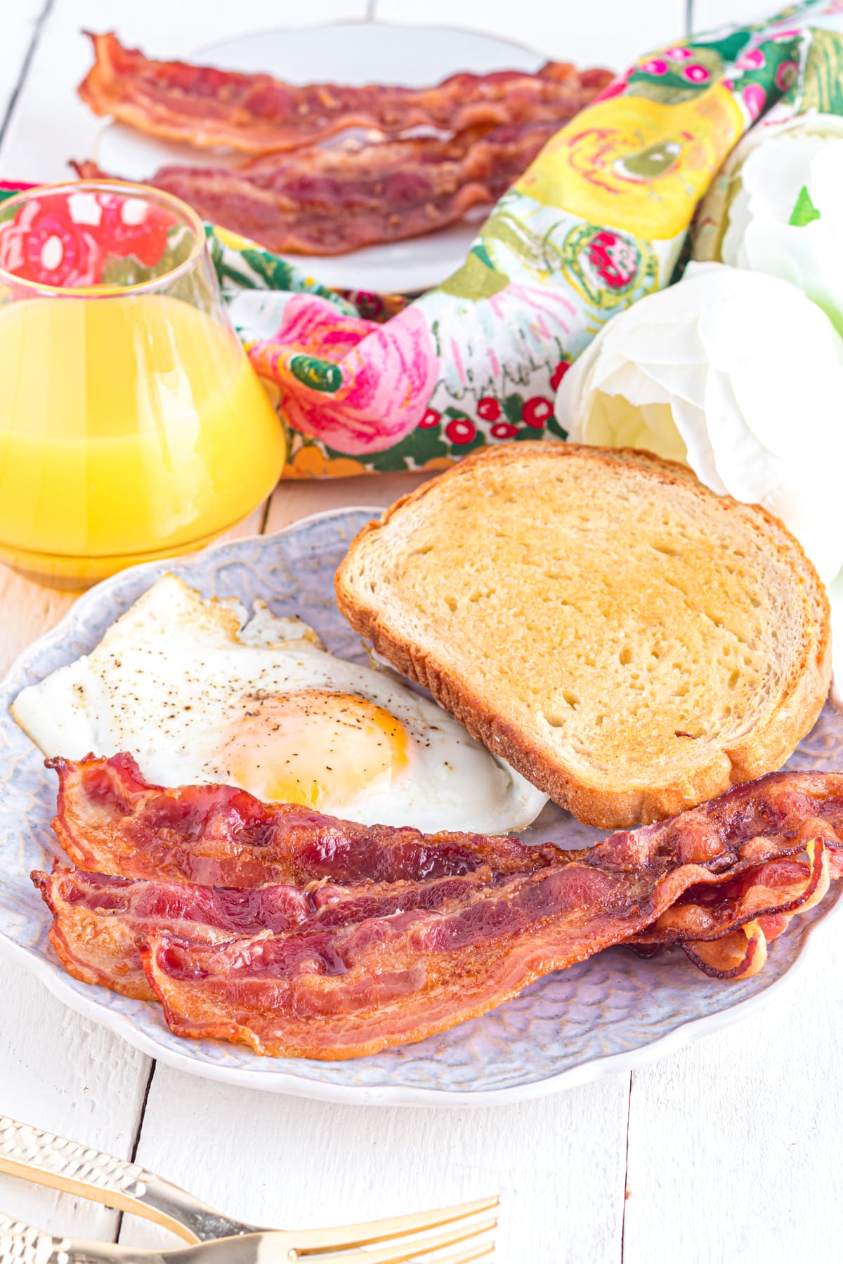 Bacon on a plate with egg and toast.