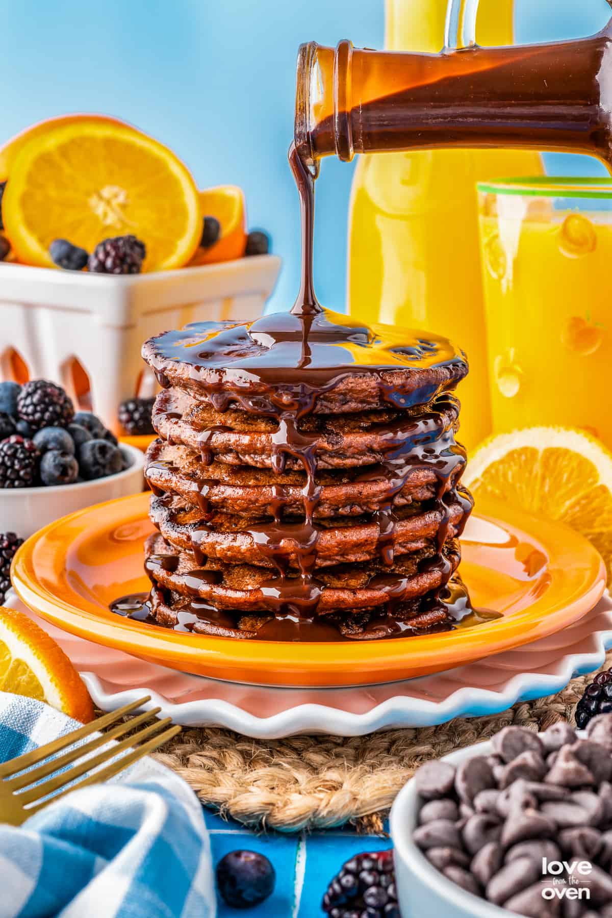 Chocolate pancakes with chocolaye syrup being poured on a plate.