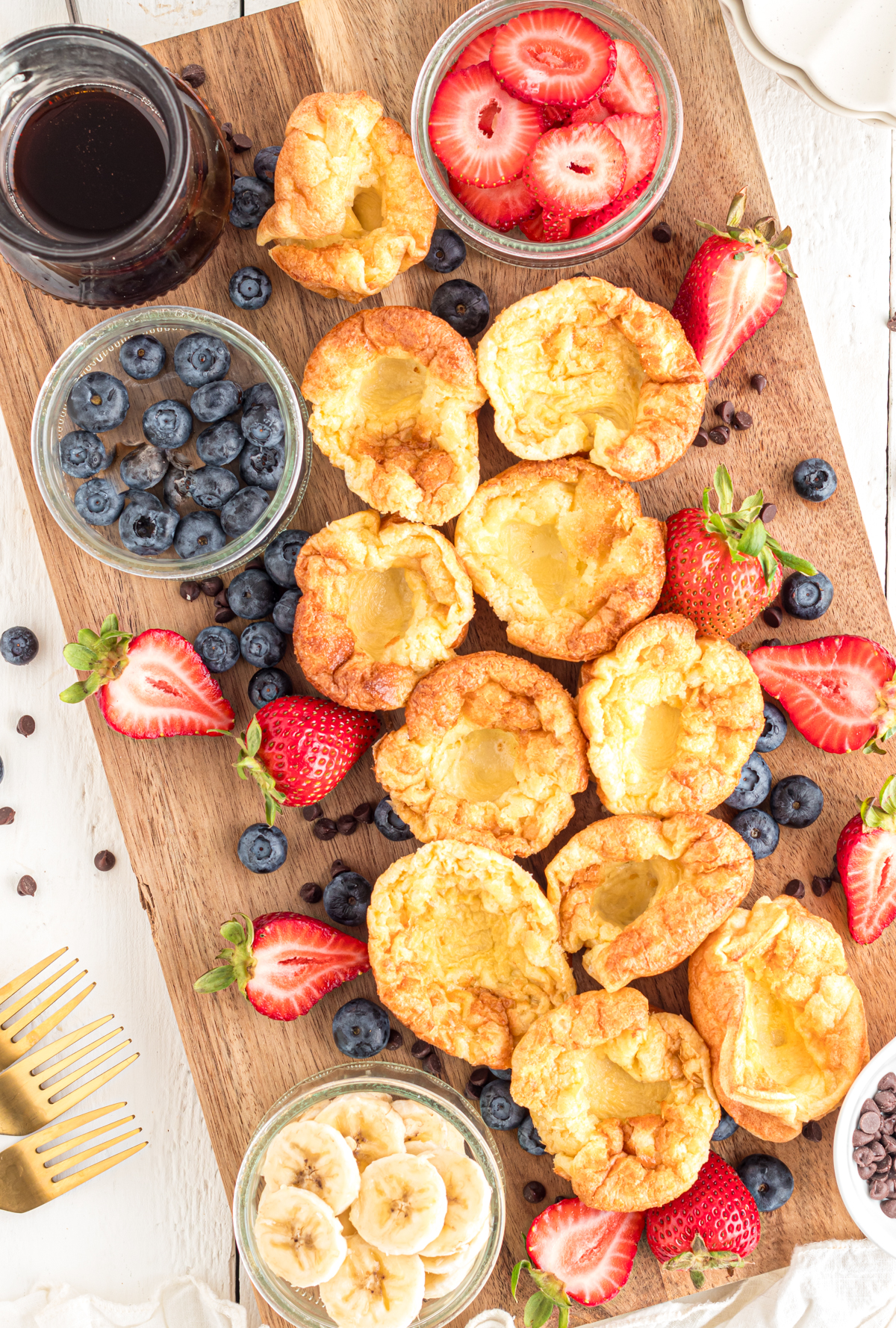 Mini dutch babies on charcuterie board with assorted toppings.