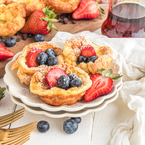 Mini Dutch babies on a plate with various toppings.