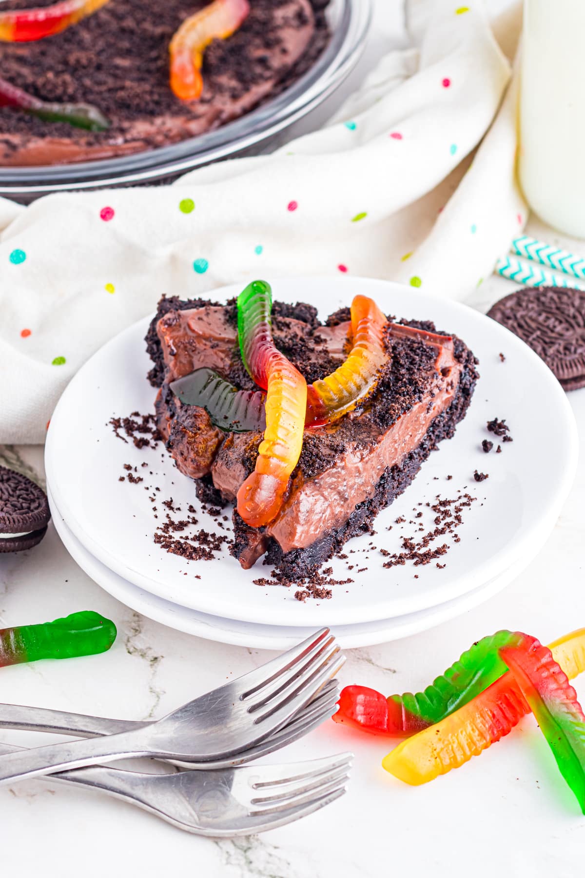 Slice of dirt pie on plate topped with gummy worms.