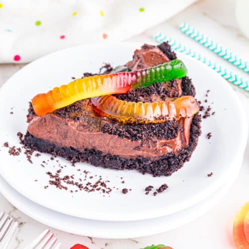 Slice of dirt pie on plate topped with gummy worms.