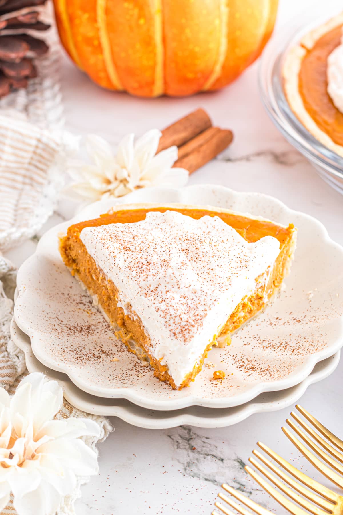 Slice of pumpkin cream pie on a scalloped plate.