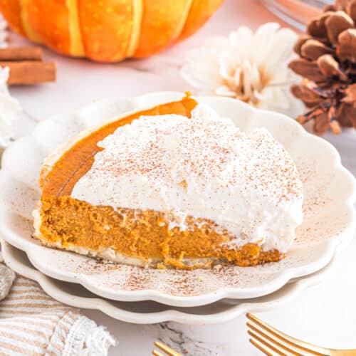 Slice of pumpkin cream pie on scalloped plate.