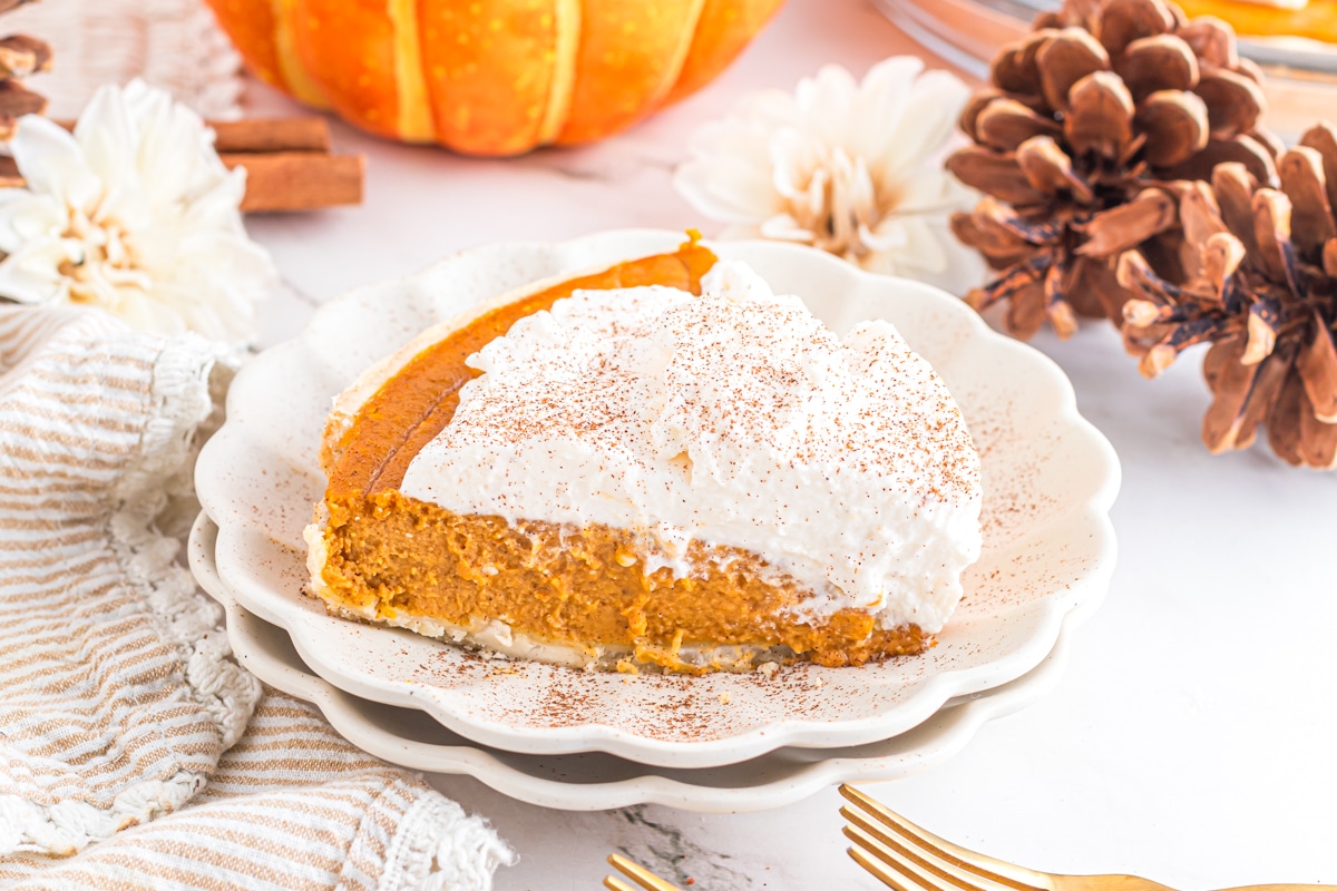 Slice of pumpkin cream pie on scalloped plate.