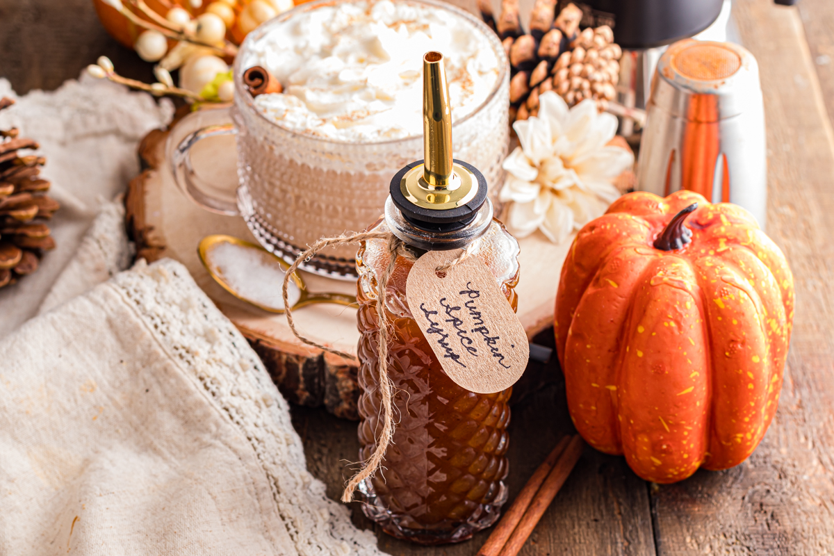 Pumpkin Spice Syrup on the table with a spice latte tank in Mug.