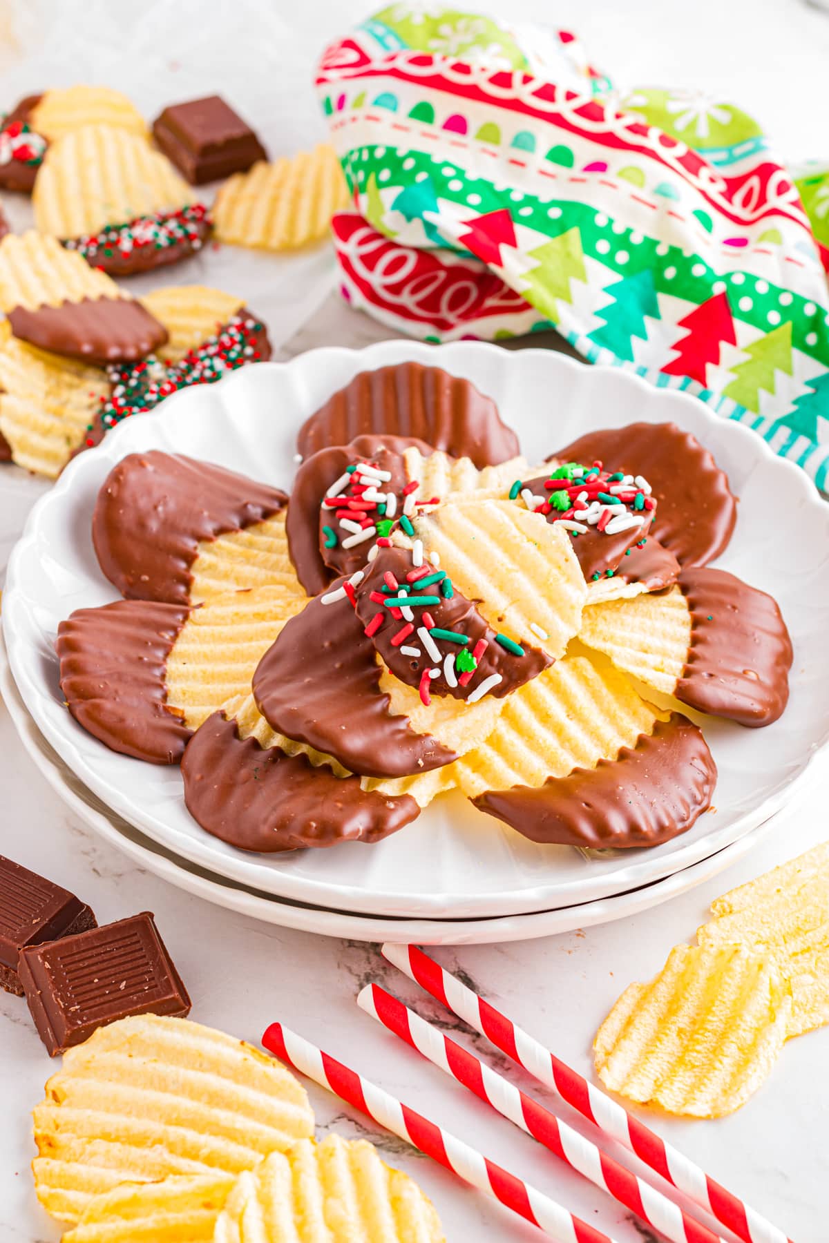 Chocolate covered potato chips on a scalloped plate on festive table.
