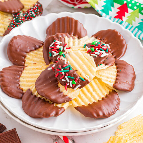 Chocolate covered potato chips with sprinkles on a colorful white plate on a holiday table.