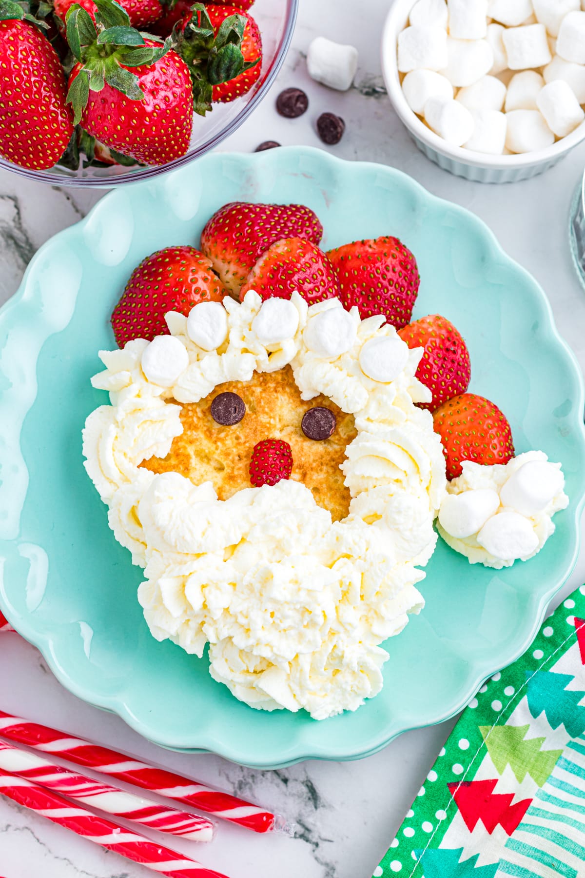 Santa pancake on a blue scalloped plate on a festive table.