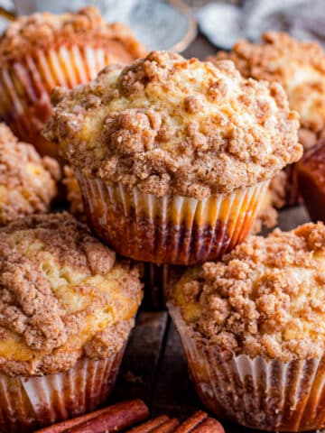 Stacked cinnamon streusel muffins on table.