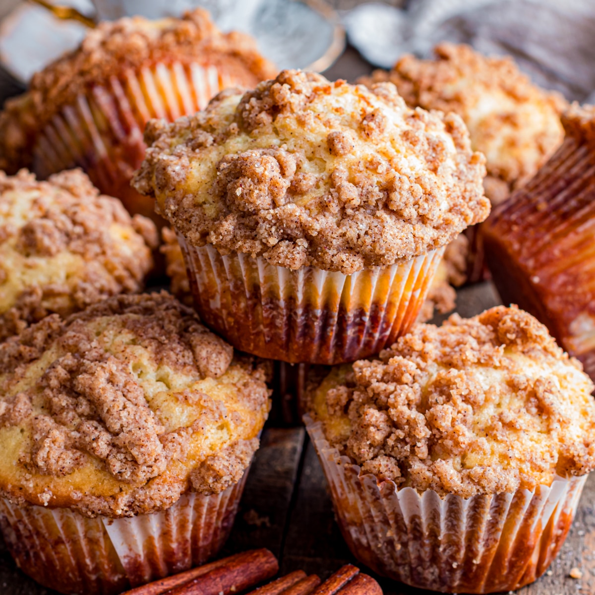 Stacked cinnamon streusel muffins on table.